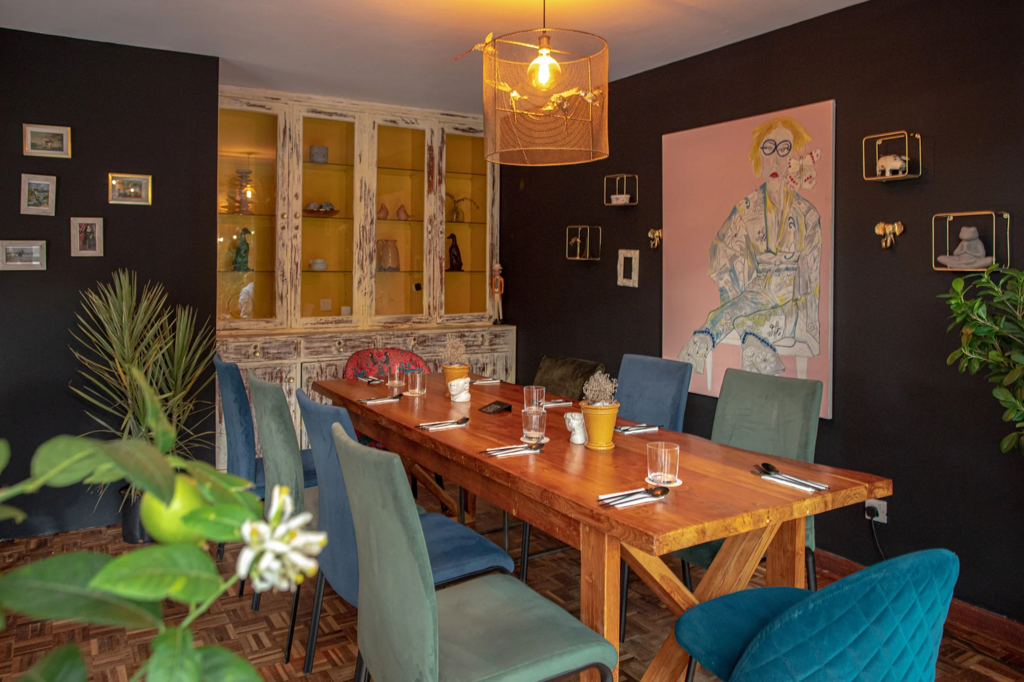 Ate's eclectic dining room, set for guests with colourful chairs and a long wooden table